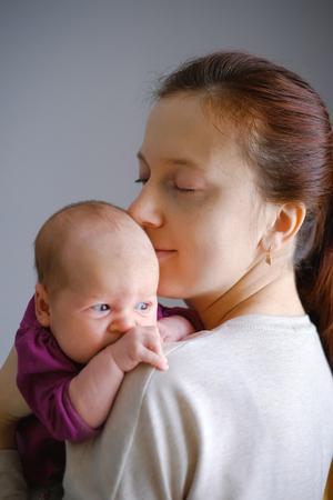 Young mother feel happiness and love emotion. Mom kissing and sweet hugging her babyの写真素材