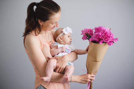 Happy young family. Mother and her daughter glad of flowers bouquetの写真素材