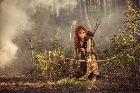 Warrior medieval woman with bow hunting in mystery forestの写真素材