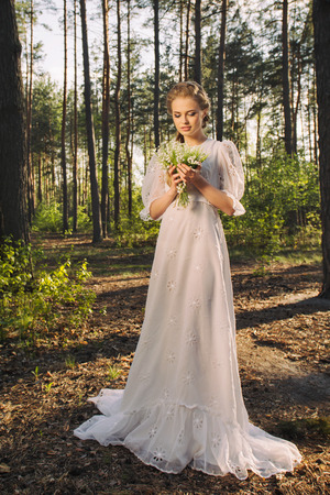 Happy woman in vintage white dress walking in forest and enjoying the natureの写真素材
