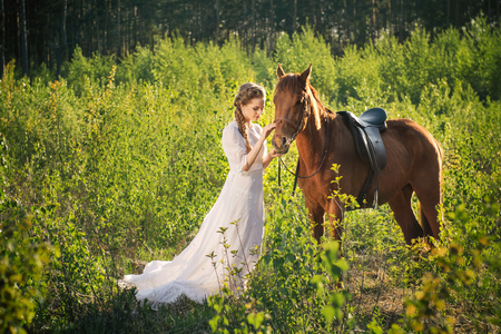 Woman standing with horse near forest and touching to faceの写真素材