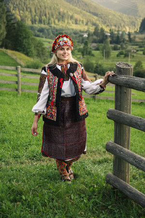 Beautiful caucasian woman wearing ethnic and traditional of the Carpathian mountain Ukrainian clothes. Village background in the autumn.の写真素材