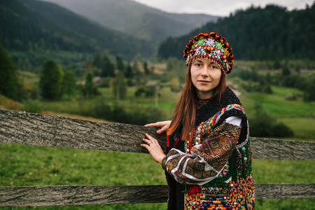Beautiful caucasian woman wearing ethnic and traditional of the Carpathian mountain Ukrainian clothes. Village background in the autumn.の写真素材