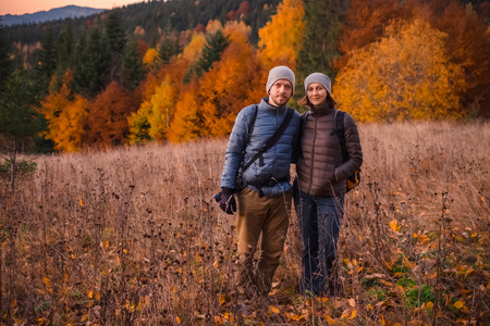 Happy couple feel freedom and enjoy the beautiful autumn forest in the mountainsの写真素材