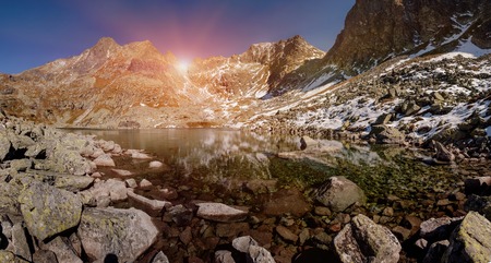 Panoramic view on Crystal mountain lake landscape with snowy Rysy peaks on background at sunset, Slovakia.の写真素材