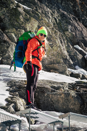 Female hiker climbing up on ladder to the mountain top in winter. Rysy. Slovakia.の写真素材
