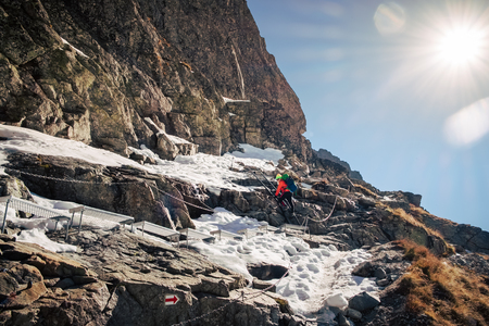 Female hiker climbing up on ladder to the mountain top in winter. Rysy. Slovakia.の写真素材