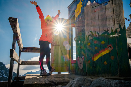 Poprad, Slovakia - October 2, 2017: Woman hiker happy with raised up hands near unique mountain altitude toilet. Travel destination scenes in High tatras mountain in Slovakiaのeditorial素材