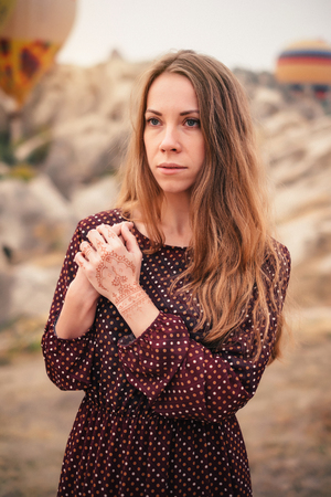 Closeup woman portrait with beautiful eyes and mehendi henna tattoo on hand at autumnの写真素材