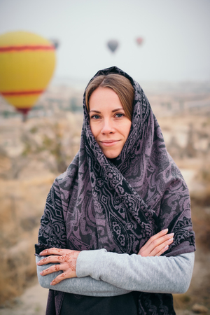 Closeup woman portrait with beautiful eyes and mehendi henna tattoo on hand in Cappadocia landscape and hot air balloon on  at sunriseの写真素材