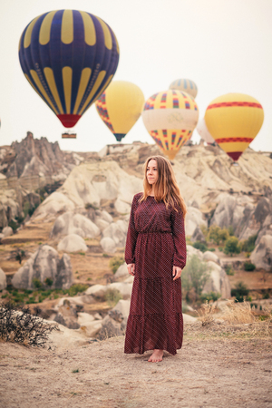 Beautiful woman enjoying amazing view and walking in Cappadocia landscape with hot air balloonの写真素材