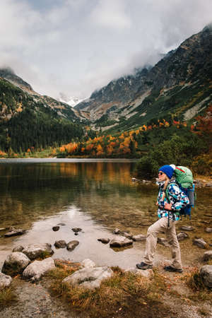 Young hiker in colorful mountain landscape at gold autumn near Popradske Pleso lake in High Tatras, Slovakiaの写真素材