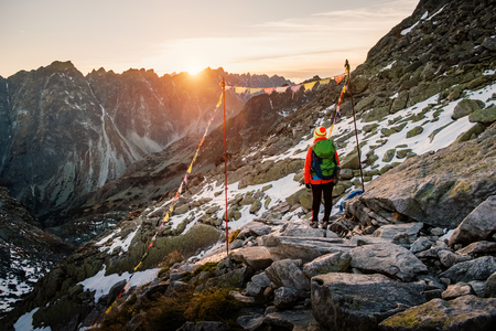 Young hiker in colorful fantastic mountain landscape and gate of prayer flags at gold sunset near Rysy in High Tatras, Slovakiaの写真素材