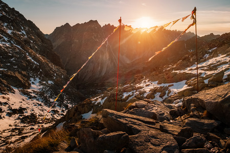 Peaceful praying flags fluttering on the wind in Rysy winter mountain at sunset in Slovakiaの写真素材