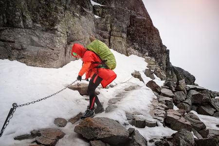 Young female tourist climbing with chain and ladder up to the top of High Tatras in Winter.の写真素材