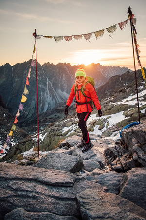 Young hiker in colorful fantastic mountain landscape and gate of prayer flags at gold sunset near Rysy in High Tatras, Slovakiaの写真素材