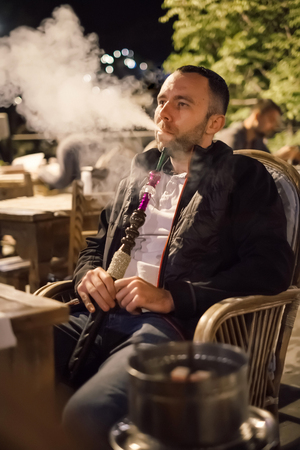 Handsome tourist man enjoy hookah while traveling in Istanbul, Turkey. High ISO shooting with grainの写真素材