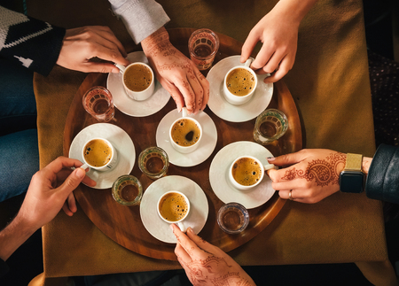 Group of people with henna mehndi tattoo on the hands drinking turkish coffey, top viewの写真素材