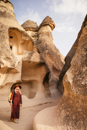 Young tourist woman hiking and enjoying mountain desert landscape while traveling in zelve open air museum in Cappadocia, turkeyの写真素材