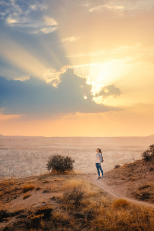 Small tourist people in big beautiful mountain landscape and sunset sky in Cappadocia rose valley enjoy view while traveling in Turkeyの写真素材