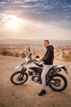 Handsome man riding and explore Cappadocia mountain valley landscape on enduro motorcycle at sunset. Travel to Turkeyの写真素材