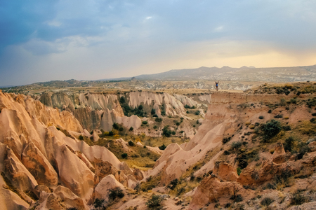 Small tourist people in big beautiful mountain landscape and sunset sky in Cappadocia rose valley enjoy view while traveling in Turkeyの写真素材