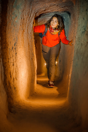 Beautiful tourist woman explore long narrow tunnel in ancient Derinkuyu underground cave city. Travel to Turkeyの写真素材