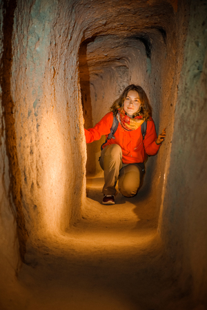Beautiful tourist woman explore long narrow tunnel in ancient Derinkuyu underground cave city. Travel to Turkeyの写真素材