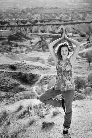 Woman practice tree yoga pose in nature. Black and white Cappadocia mountain landscape with beautiful skyの写真素材
