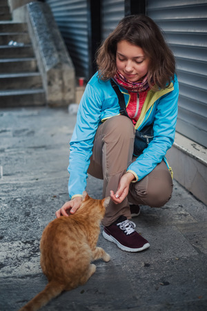 Portrait of beautiful woman that paying with red homeless cat. Love and fun emotion for petsの写真素材