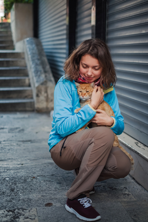 Portrait of beautiful woman that paying with red homeless cat. Love and fun emotion for petsの写真素材