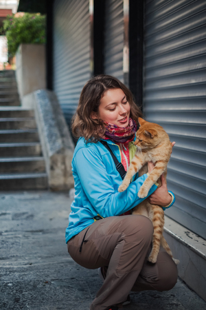 Portrait of beautiful woman that paying with red homeless cat. Love and fun emotion for petsの写真素材