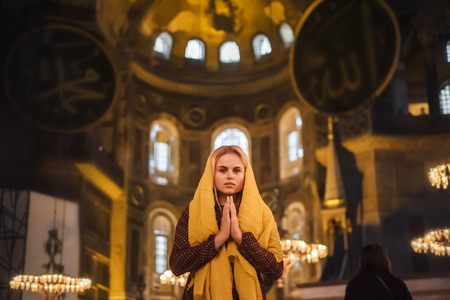 Christian Religion Concept. Young woman praying and feel God blessing in her heart in Hagia Sophia, Istanbul, Turkeyの写真素材