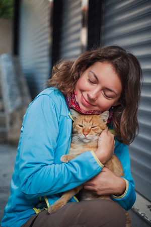 Portrait of beautiful woman that paying with red homeless cat. Love and fun emotion for petsの写真素材