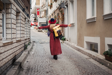 Happy beautiful tourist woman in hat and dress walking on Istanbul street and enjoy arabic city architecture, Turkeyの写真素材