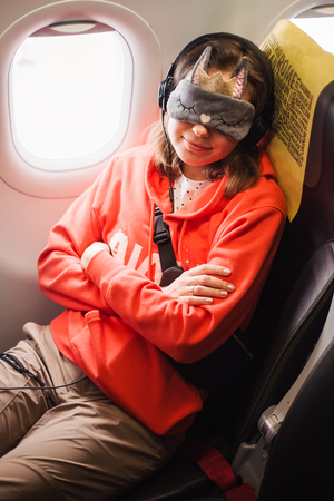 Tourist woman passenger fly in airplane and sleep in eyes mask near the windowの写真素材
