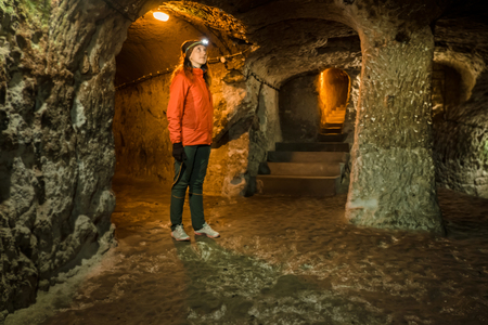 Beautiful tourist woman explore long narrow tunnel in ancient Derinkuyu underground cave city. Travel to Turkeyの写真素材