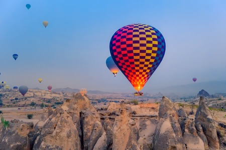 Close-up colorful big hot air balloons flying over beautiful Goreme village landscape at sunrise. Cappadocia is famous travel destination with beautiful limestone mountains, Turkeyの写真素材