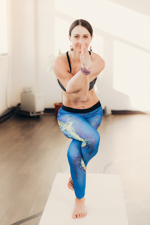 Happy smiling caucasian yoga instructor practicing yoga on in white studio at the morningの写真素材