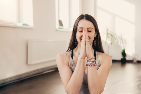 Happy smiling caucasian female yoga instructor doing namaste hand gesture at studio class. Healthy lifestyle concept.の写真素材