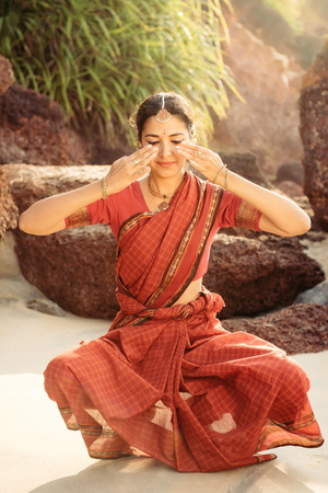 Indian classical dance Bharatanatyam performed by beautiful woman in traditional clothes at sunsetの写真素材