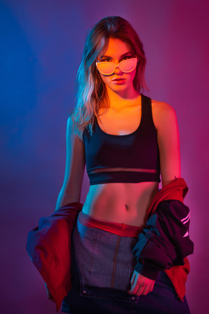 Retro style fashionable woman posing in purple, blue, and pink lights. Fashion back to 80s - 90s new trend conceptの写真素材