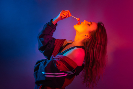 Retro style fashionable woman posing in purple, blue, and pink lights. Fashion back to 80s - 90s new trend conceptの写真素材