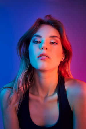 Retro style fashionable woman posing in purple, blue, and pink lights. Fashion back to 80s - 90s new trend conceptの写真素材