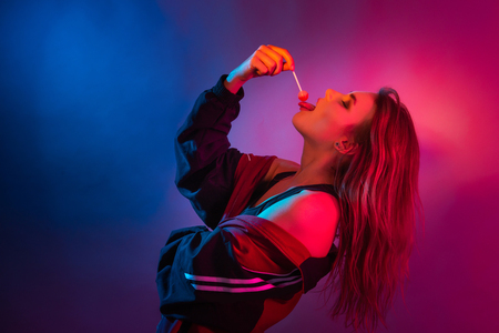 Retro style fashionable woman posing in purple, blue, and pink lights. Fashion back to 80s - 90s new trend conceptの写真素材