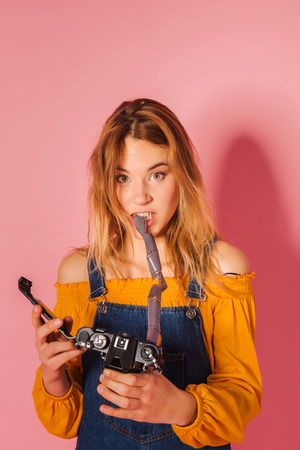 Funny retro styled fashionable woman portrait with vintage film camera on pink background. Fashion back to 80s - 90s new trend conceptの写真素材