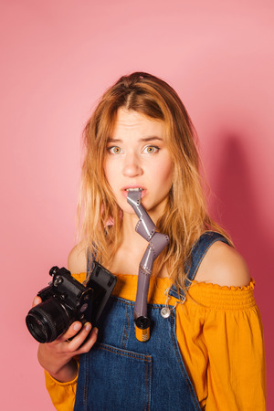 Funny retro styled fashionable woman portrait with vintage film camera on pink background. Fashion back to 80s - 90s new trend conceptの写真素材