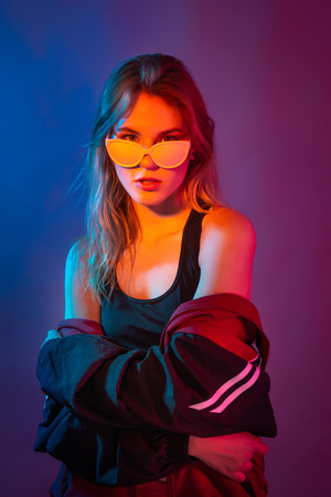 Retro style fashionable woman posing in purple, blue, and pink lights. Fashion back to 80s - 90s new trend conceptの写真素材