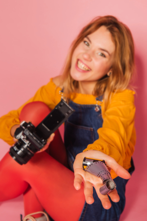 Positive retro styled fashionable woman in sport jacket and jeans with vintage cassette player on red background. Fashion back to 80s - 90s new trend conceptの写真素材