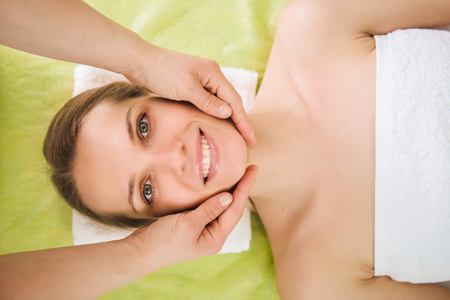 Beautiful woman relaxing and enjoying a head massage in a spa centerの写真素材